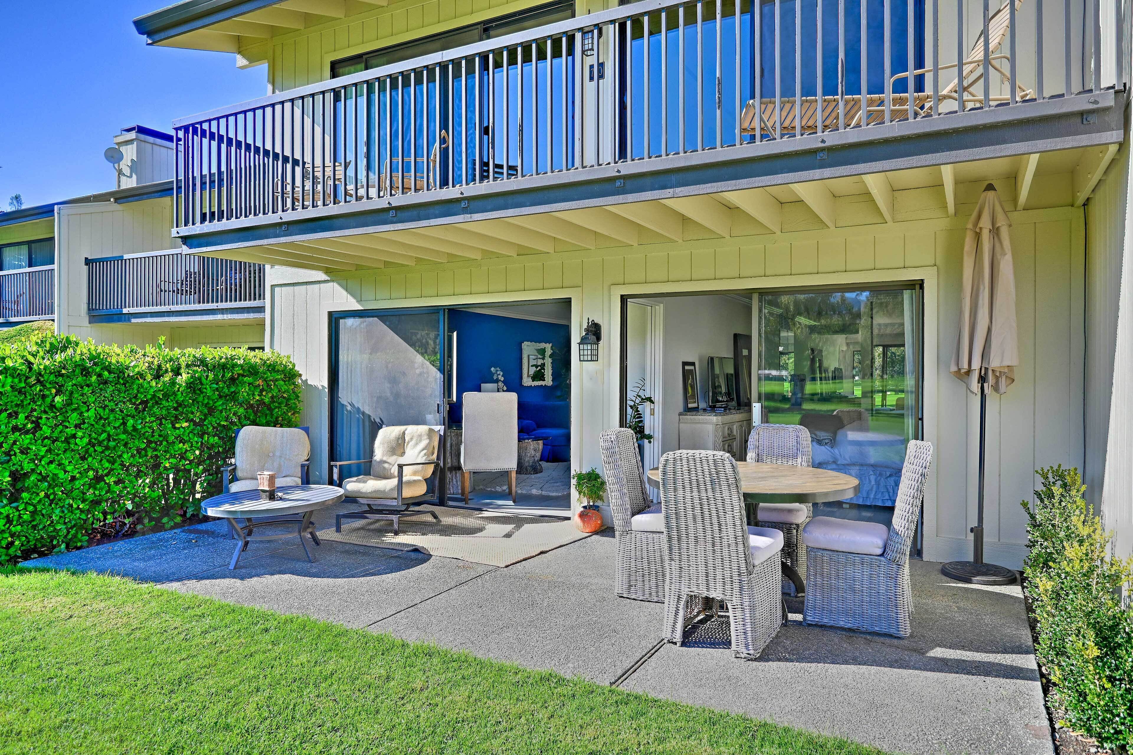 A two-story building with a balcony, outdoor seating area, and a large window.