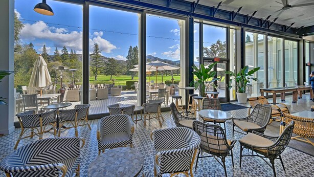 A spacious indoor seating area with large windows offering a view of a golf course and mountains. - Bright & Airy Napa Condo W/patio on Golf Course! (Napa)