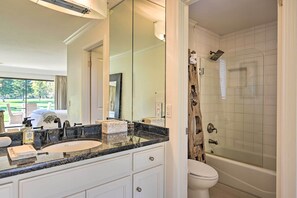 A bathroom with a large mirror, a sink with a marble countertop, a toilet, and a glass-enclosed shower. - Bright & Airy Napa Condo W/patio on Golf Course! (Napa)