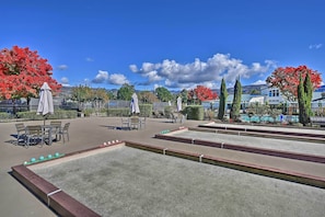 A courtyard with a croquet lawn, outdoor seating, and red flowering trees. - Bright & Airy Napa Condo W/patio on Golf Course! (Napa)