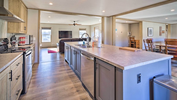 A spacious kitchen with wooden cabinets, a large island, and a dining area with a table and chairs. - Close to Marinas: Bernice Home w/ Large Yard (Afton)