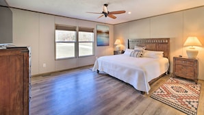 A bedroom with a large bed, a ceiling fan, a window, and a nightstand with lamps. - Close to Marinas: Bernice Home w/ Large Yard (Afton)