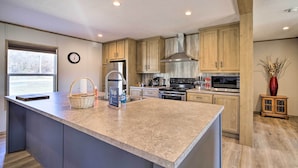 A modern kitchen with a large island, wooden cabinets, stainless steel appliances, and a view of the outdoors. - Close to Marinas: Bernice Home w/ Large Yard (Afton)