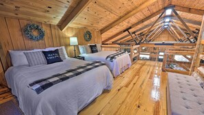 A cozy attic bedroom with wooden beams, two beds, a view of the outdoors, and a wreath on the wall. - Waterfront Deck: Home on Ouachita River! (Arkadelphia)
