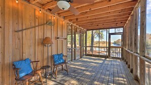 A wooden deck with two rocking chairs and a table, overlooking a scenic outdoor area. - Waterfront Deck: Home on Ouachita River! (Arkadelphia)