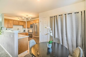 A compact kitchen with wooden cabinets, a central island, and a dining area with a round table and chairs.