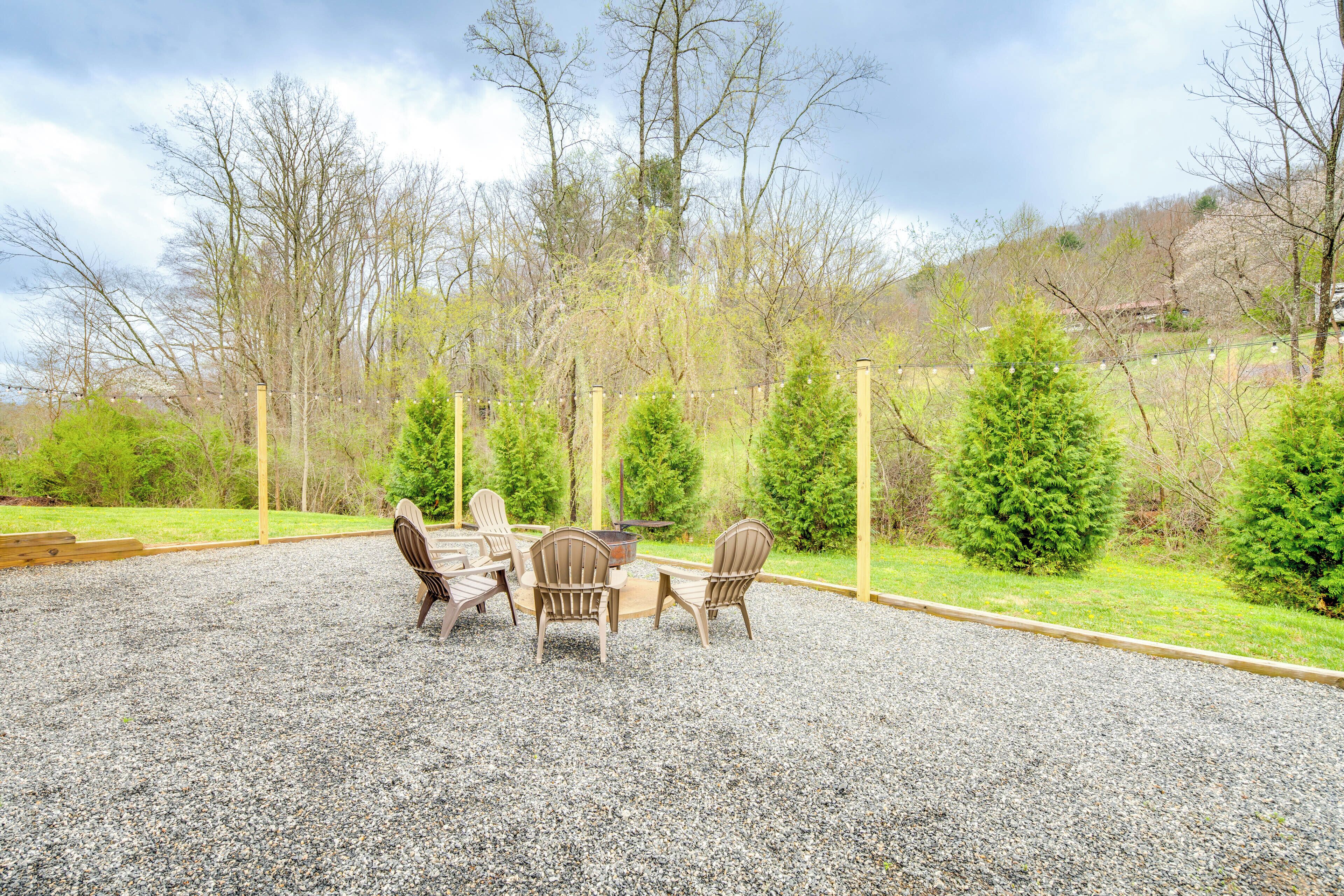 An outdoor seating area with a table and chairs, surrounded by a gravel ground and trees.
