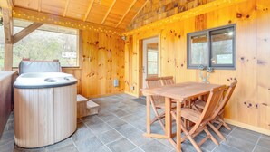 A wooden cabin interior with a hot tub, wooden dining table, and chairs. - Sawyers Cabin w/ Hot Tub in Blue Ridge Mtns! (Fletcher)