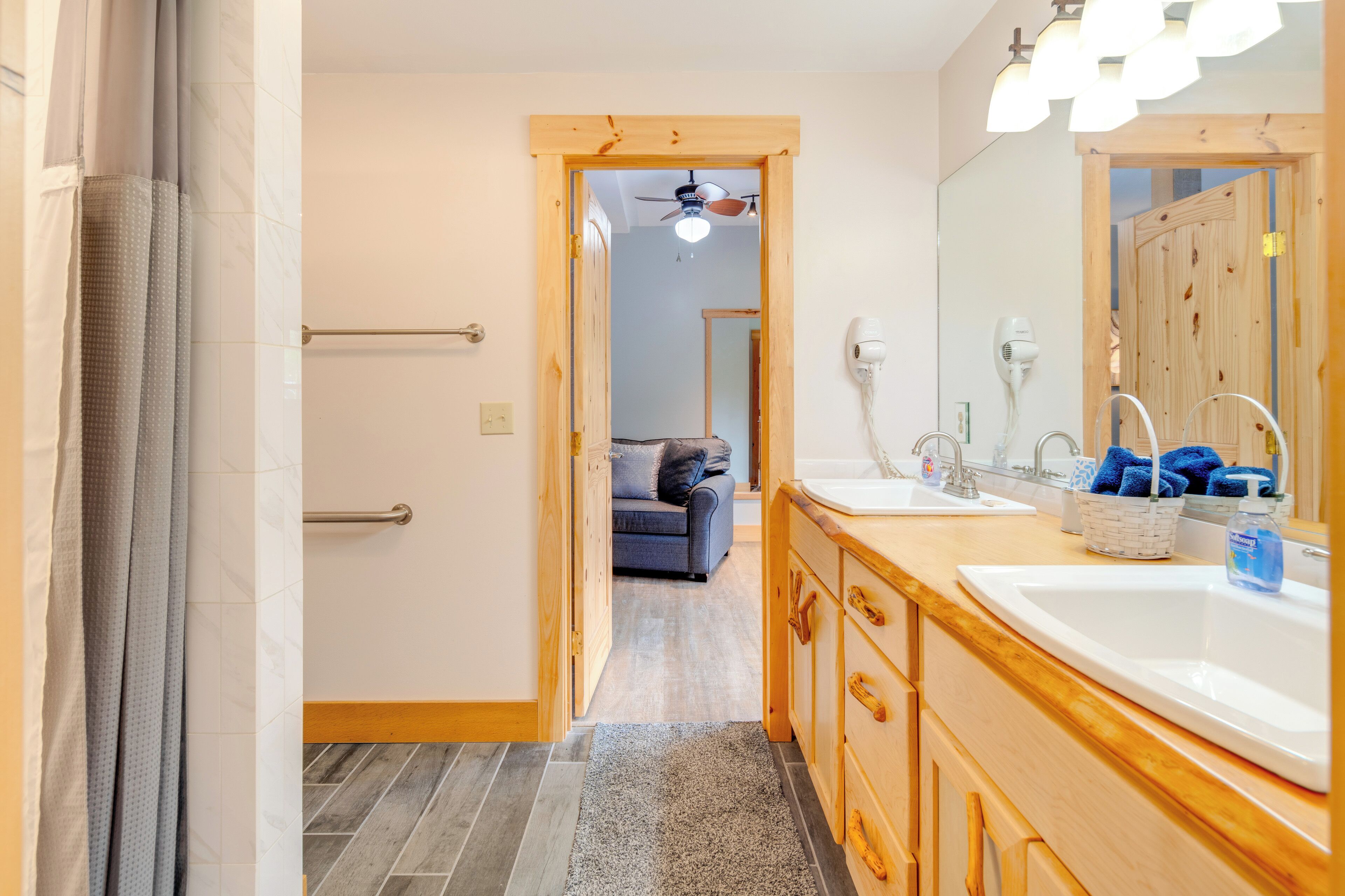 Un baño con tocador de madera, un espejo grande, un ventilador de techo y una zona de ducha.