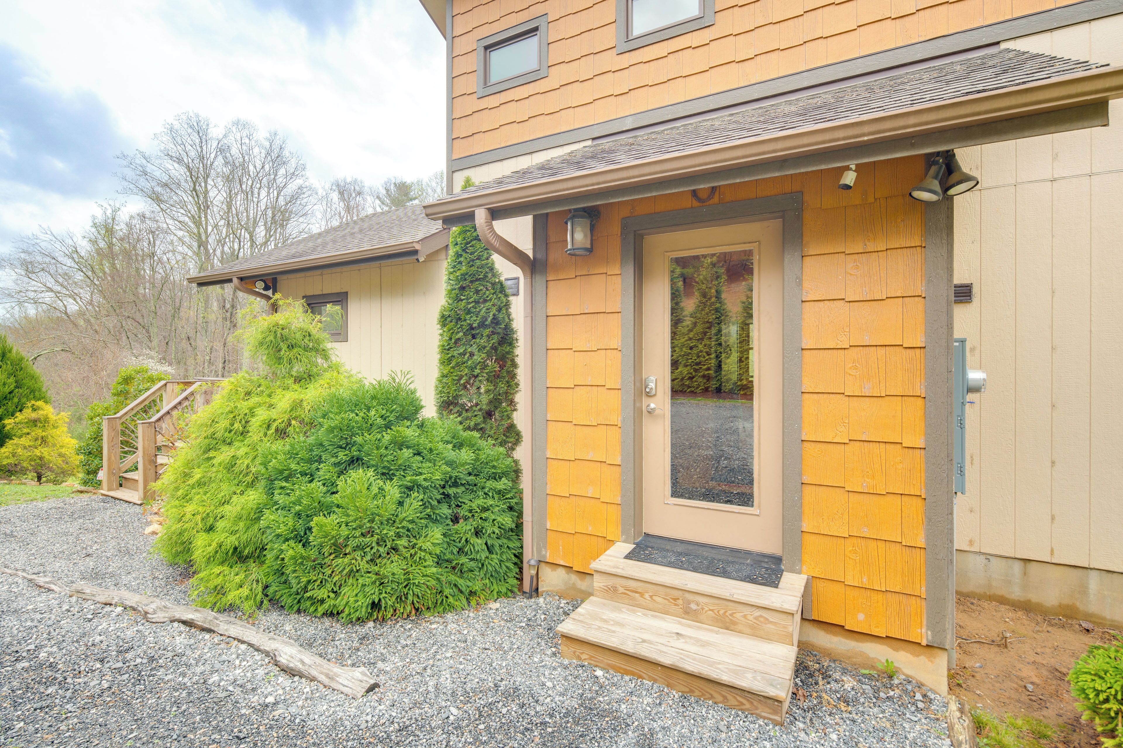 Une maison à deux étages avec une façade en bois, un porche à l’avant et une allée gravillonnée.