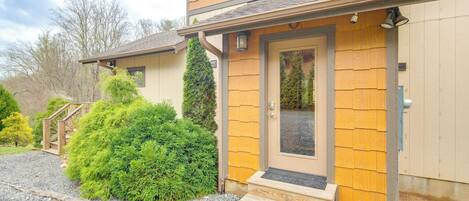 Une maison à deux étages avec une façade en bois, un porche à l’avant et une allée gravillonnée.