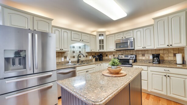 A modern kitchen with white cabinetry, stainless steel appliances, and a granite countertop.