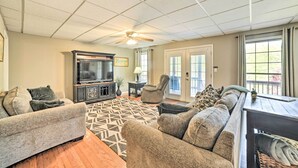 A living room with a ceiling fan, a large TV, and a sofa set.