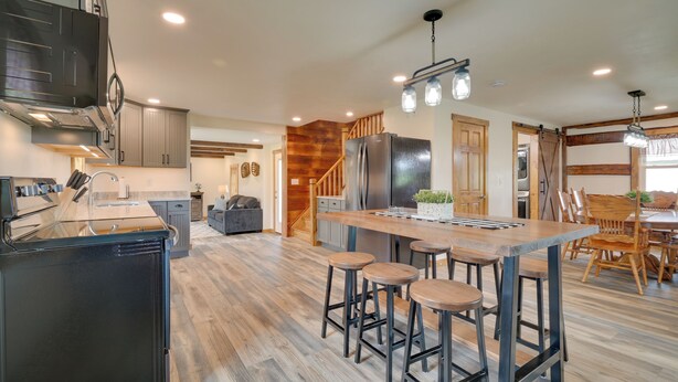 A modern kitchen with a central island, bar stools, and a large refrigerator.