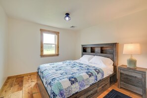 Un dormitorio con una cama de madera, una mesita de noche, una lámpara y una ventana.