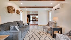A modern living room with a grey sofa, patterned armchairs, a wooden coffee table, and a patterned rug.