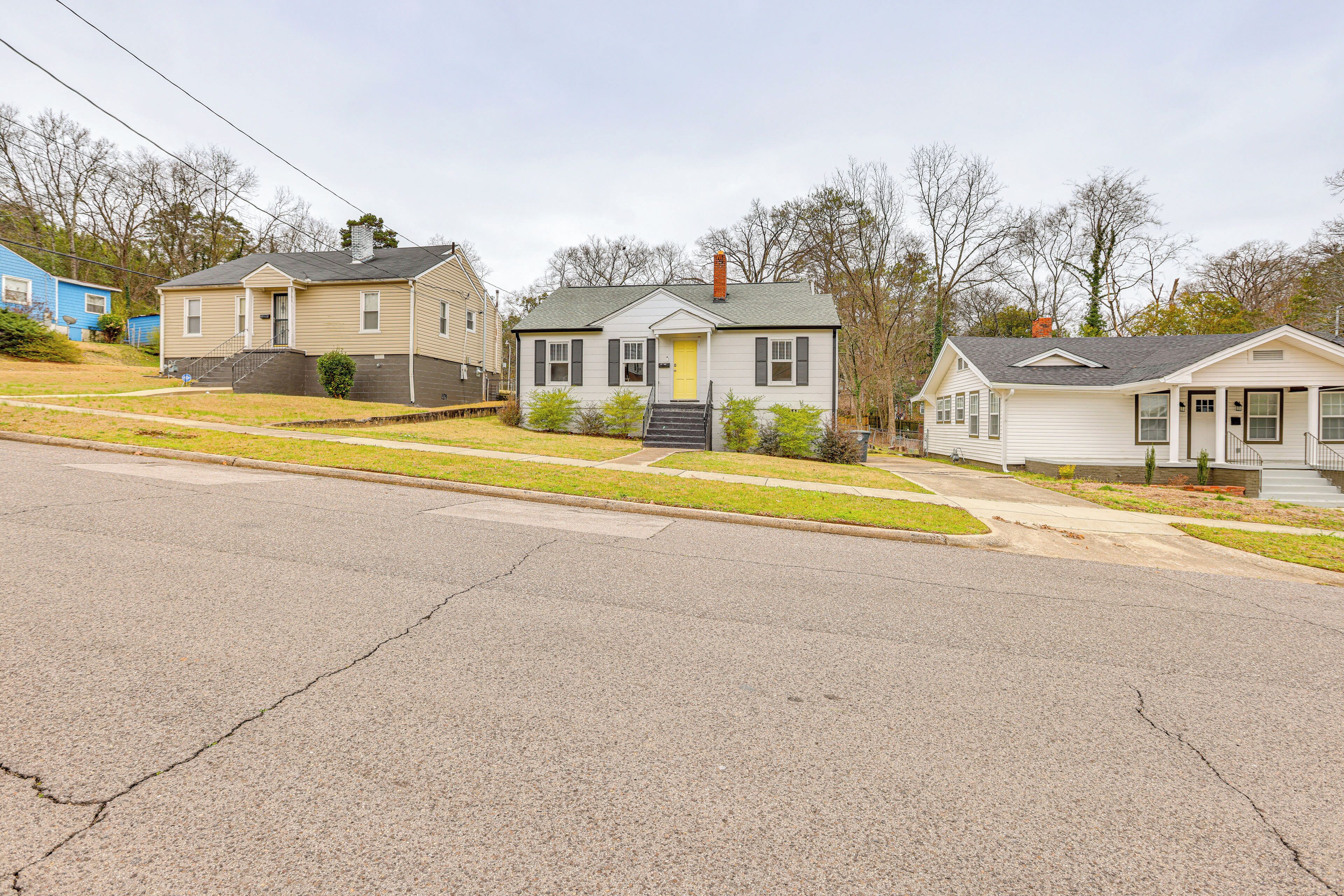 A row of single-story houses with front porches, a driveway, and a grassy lawn.