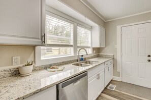 A kitchen with white cabinets, a granite countertop, a stainless steel dishwasher, and a window with blinds. - Walk to Ruffner Mountain: Family Home w/ Yard (Birmingham)