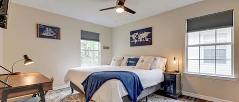 A bedroom with a bed, bedside table, lamp, and a ceiling fan.