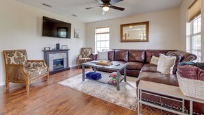 A living room with a fireplace, leather sofa, and a ceiling fan. - Charming Biloxi Vacation Rental Near Beach! (Biloxi)