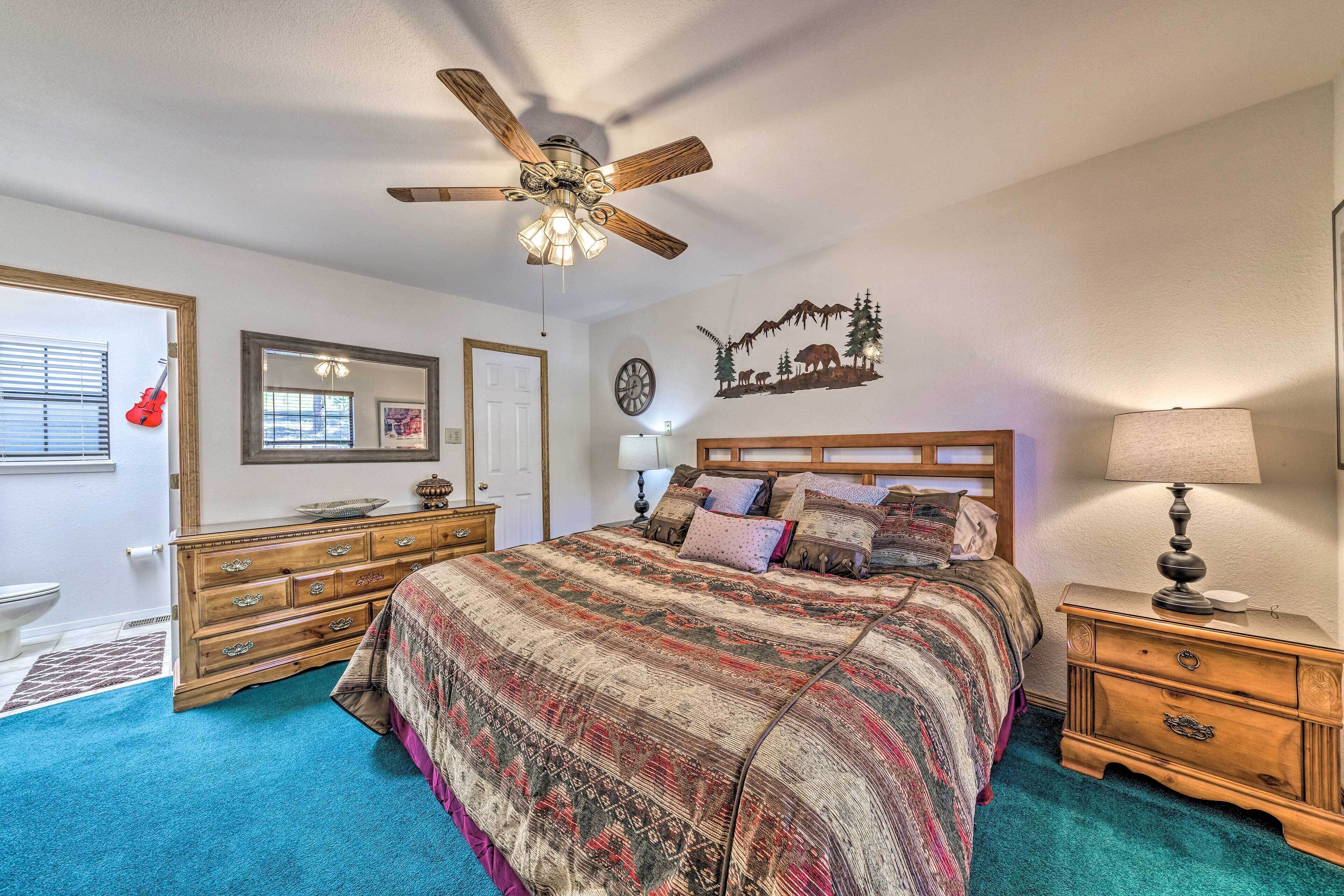 A bedroom with a large bed, wooden dresser, and a ceiling fan.