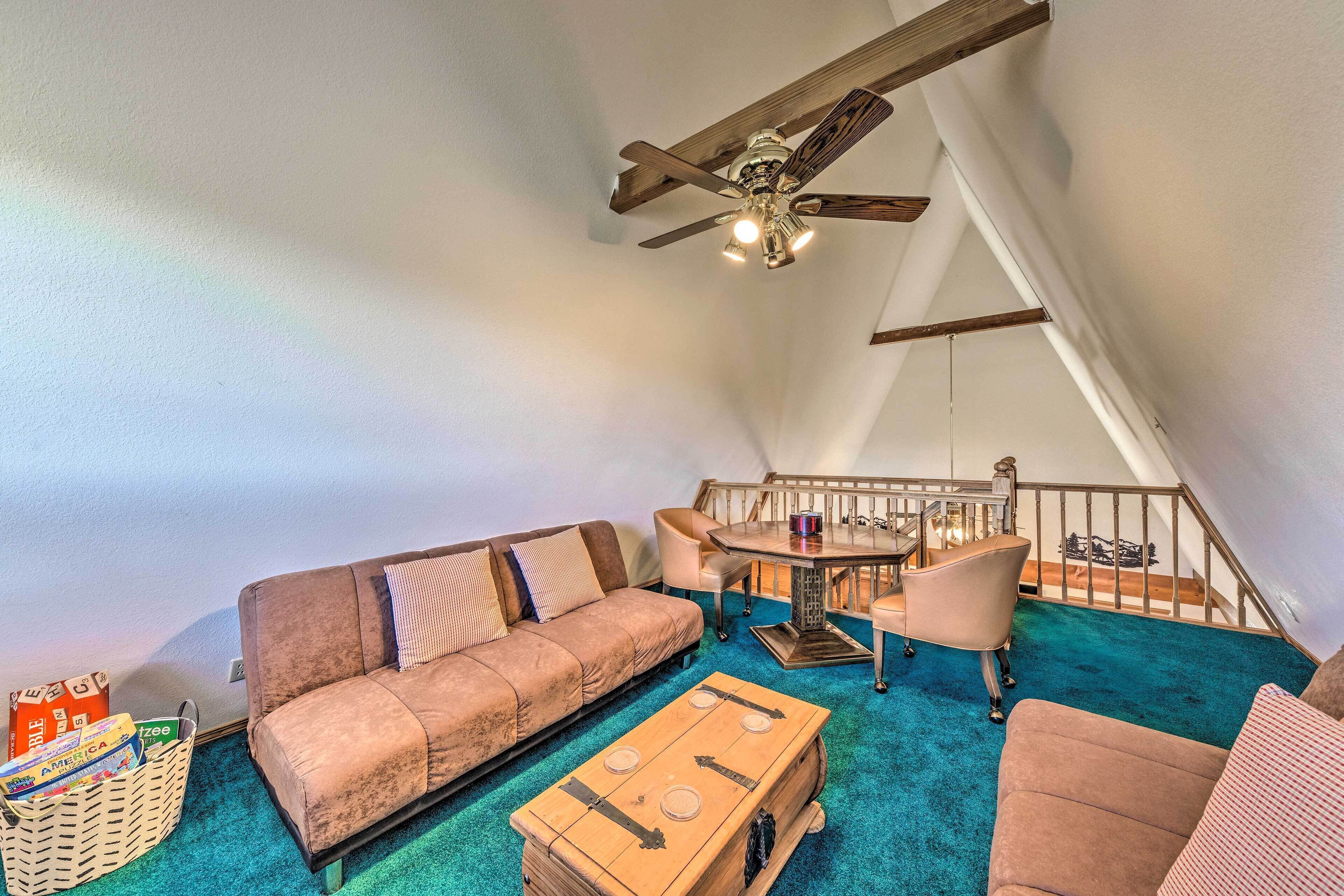 Ein gemütliches Schlafzimmer im Loft-Stil mit Deckenventilator, einer Couch, einem Couchtisch und einem Essbereich mit Stühlen.