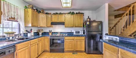 A kitchen with wooden cabinets, a stainless steel refrigerator, a microwave, and an oven.