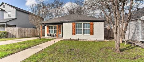 A single-story house with a front yard, a wooden fence, and a tree.