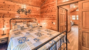 A wooden cabin bedroom with a bed, a nightstand, and a wall-mounted decorative piece. - Charming New Bern Log Cabin - Pets Welcome! (New Bern)