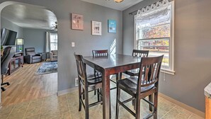 Een eetgedeelte met een houten tafel en stoelen, een kroonluchter en kunstwerken in lijsten aan de muur.