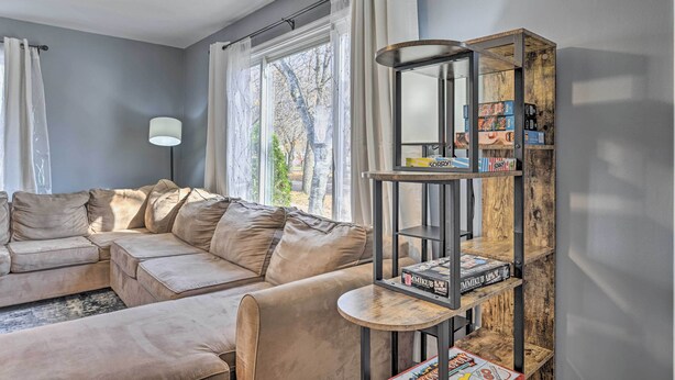 Een woonkamer met een beige modulaire bank, een houten boekenkast en een raam met gordijnen.