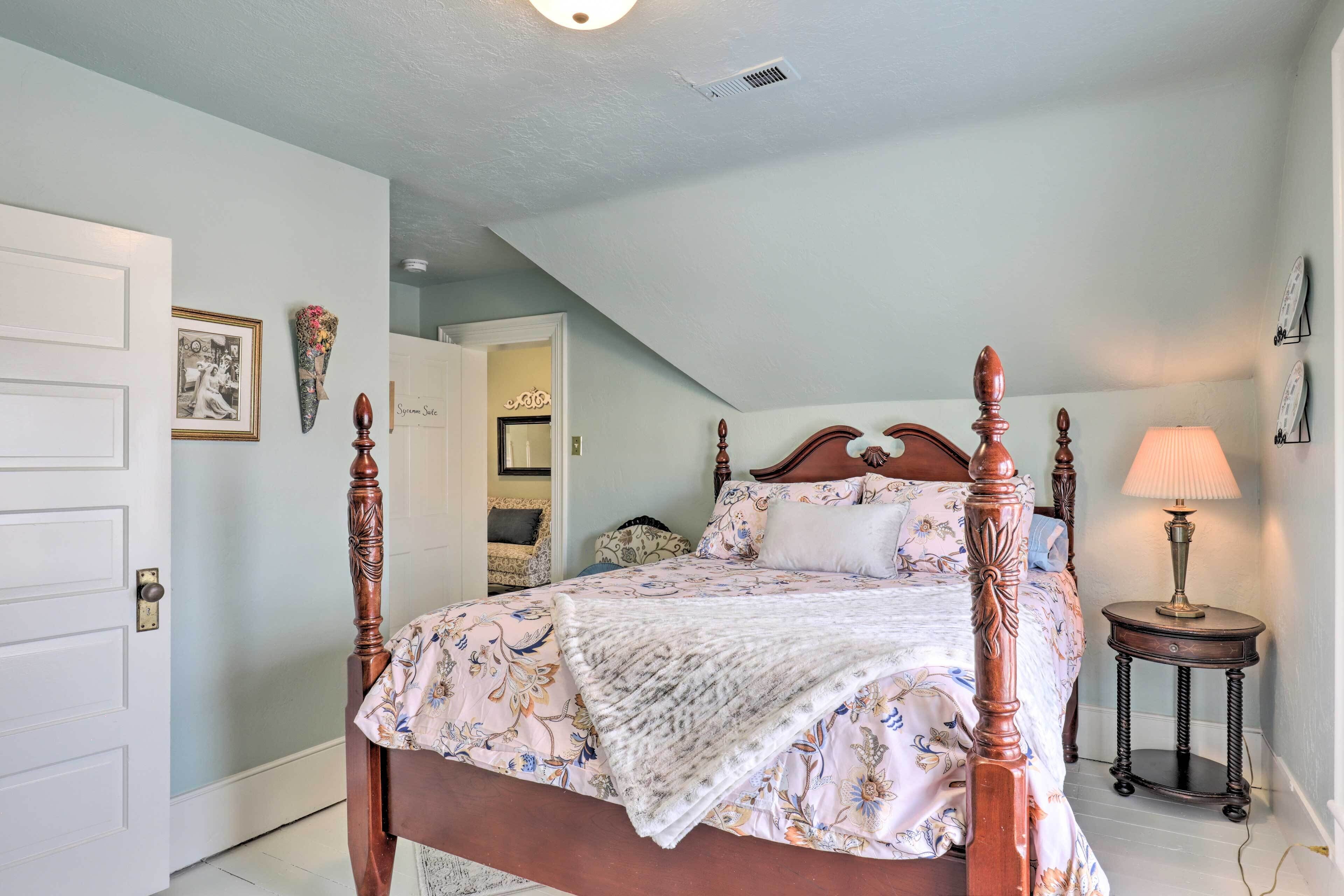 A bedroom with a four-poster bed, a bedside lamp, and a door leading to another room.