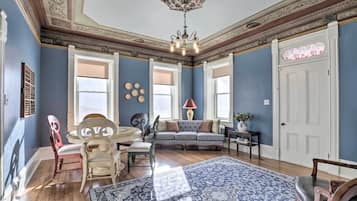 A room with a blue wall, a patterned rug, a sofa, a chandelier, and a door with a floral design.