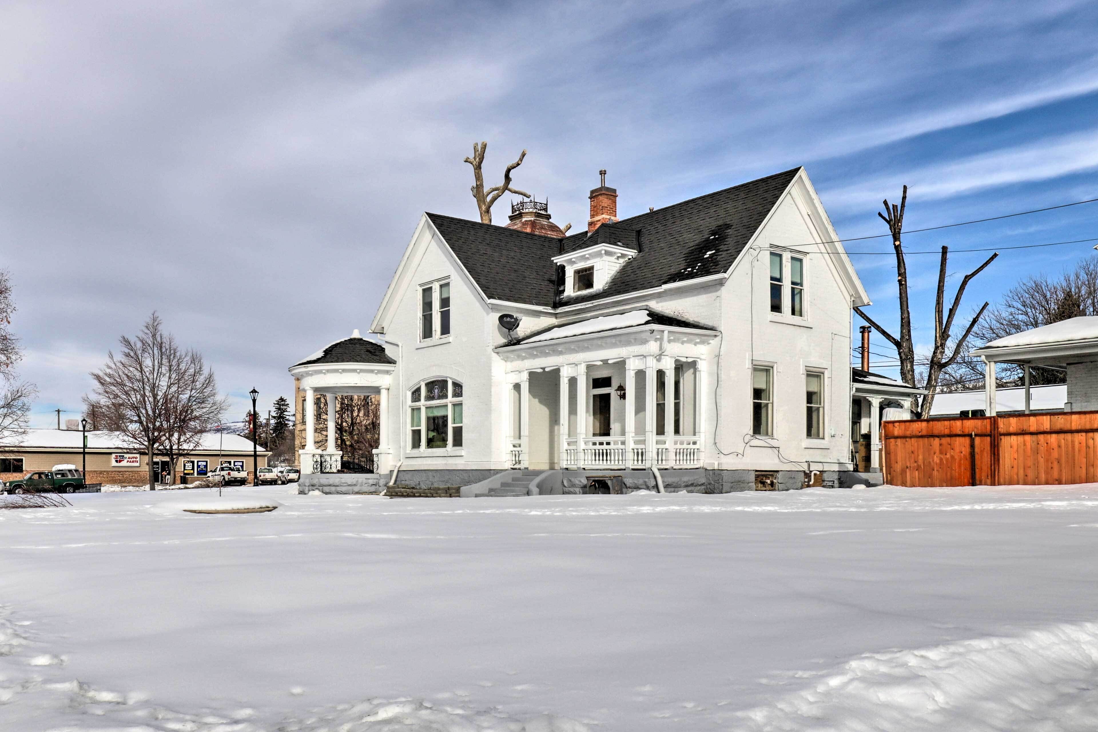 A large, two-story house with a wrap-around porch and a chimney.