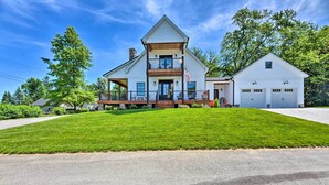 A large, single-story house with a prominent front porch, a garage, and a well-maintained lawn. - Charming Lake Erie Getaway: Walk to Beach! (North East)