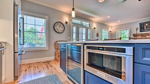 A modern kitchen with built-in appliances, large windows, and a ceiling fan. - Charming Lake Erie Getaway: Walk to Beach! (North East)