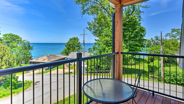 A balcony with a view of the sea, a wooden pergola, and a metal railing. - Charming Lake Erie Getaway: Walk to Beach! (North East)