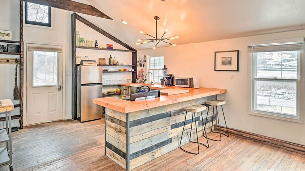 Une cuisine moderne dotée d’un îlot central en bois, d’appareils électroménagers en acier inoxydable et d’un luminaire au plafond au design original.