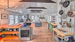 Une cuisine moderne dotée d’un îlot central, de poutres en bois et d’un porte-ustensiles fixé au mur.