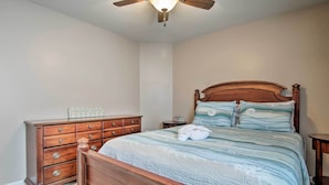 A bedroom with a wooden bed, a dresser, a nightstand, and a ceiling fan. - Great for Groups: Bayside Resort Home w/ Patio (Selbyville)