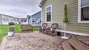 A patio with brick flooring, wicker furniture, and a green umbrella. - Great for Groups: Bayside Resort Home w/ Patio (Selbyville)