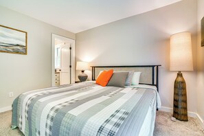 A neatly made bed with a striped quilt, a bedside lamp, and a nightstand. - 'the Trailhouse at Serendipity' in Taylor Falls (Taylors Falls)