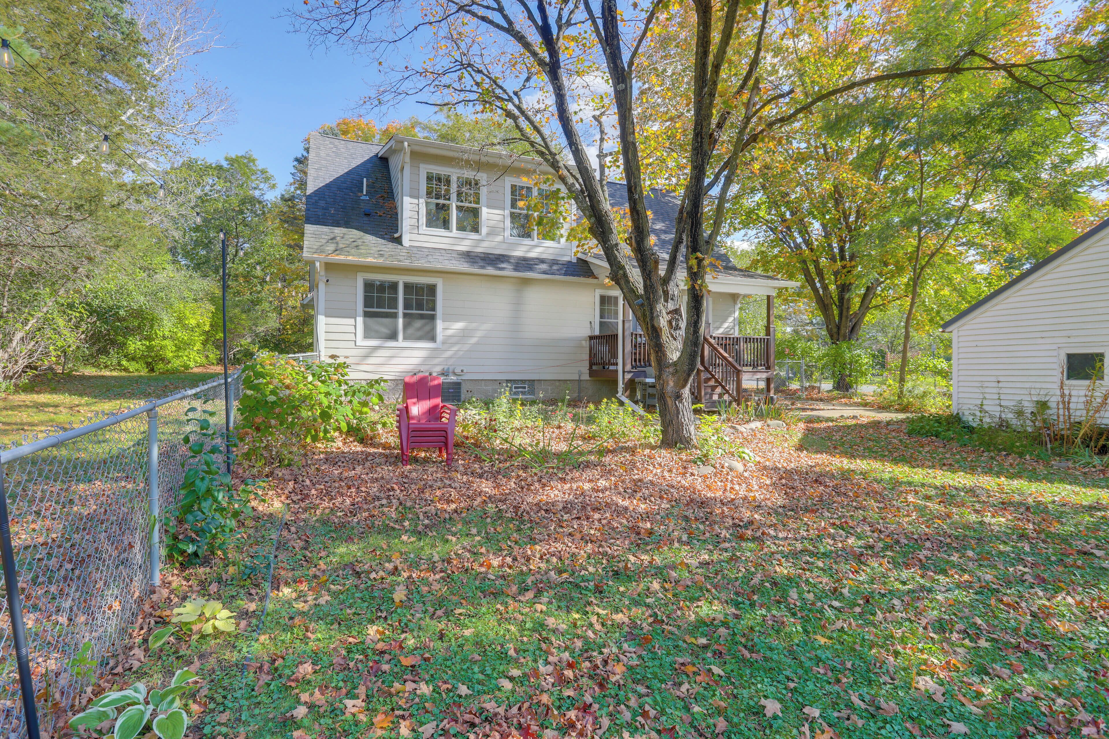 A two-story house with a front porch, surrounded by trees and a fence.