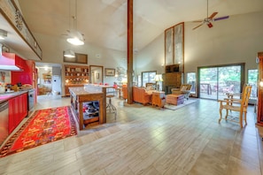 A spacious living area with a kitchen, dining area, and large windows. - Fire Pit, Peaceful Porch! Family Cabin By Old Town (San Antonio)