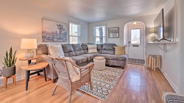 A cozy living room with a grey sectional sofa, a wicker chair, a small table with a lamp, and a patterned rug. - Central Boise Home Near Bsu, 1 Mi to Dtwn! (Boise)