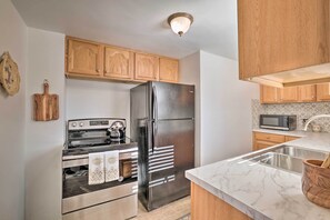Una cocina con armarios de madera, un refrigerador de acero inoxidable, una estufa y un microondas.