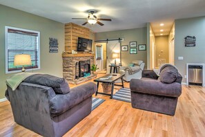 A living room with a fireplace, two sofas, a coffee table, and a television. - Country Cottage < 3 Mi to Dale Hollow Lake! (Byrdstown)