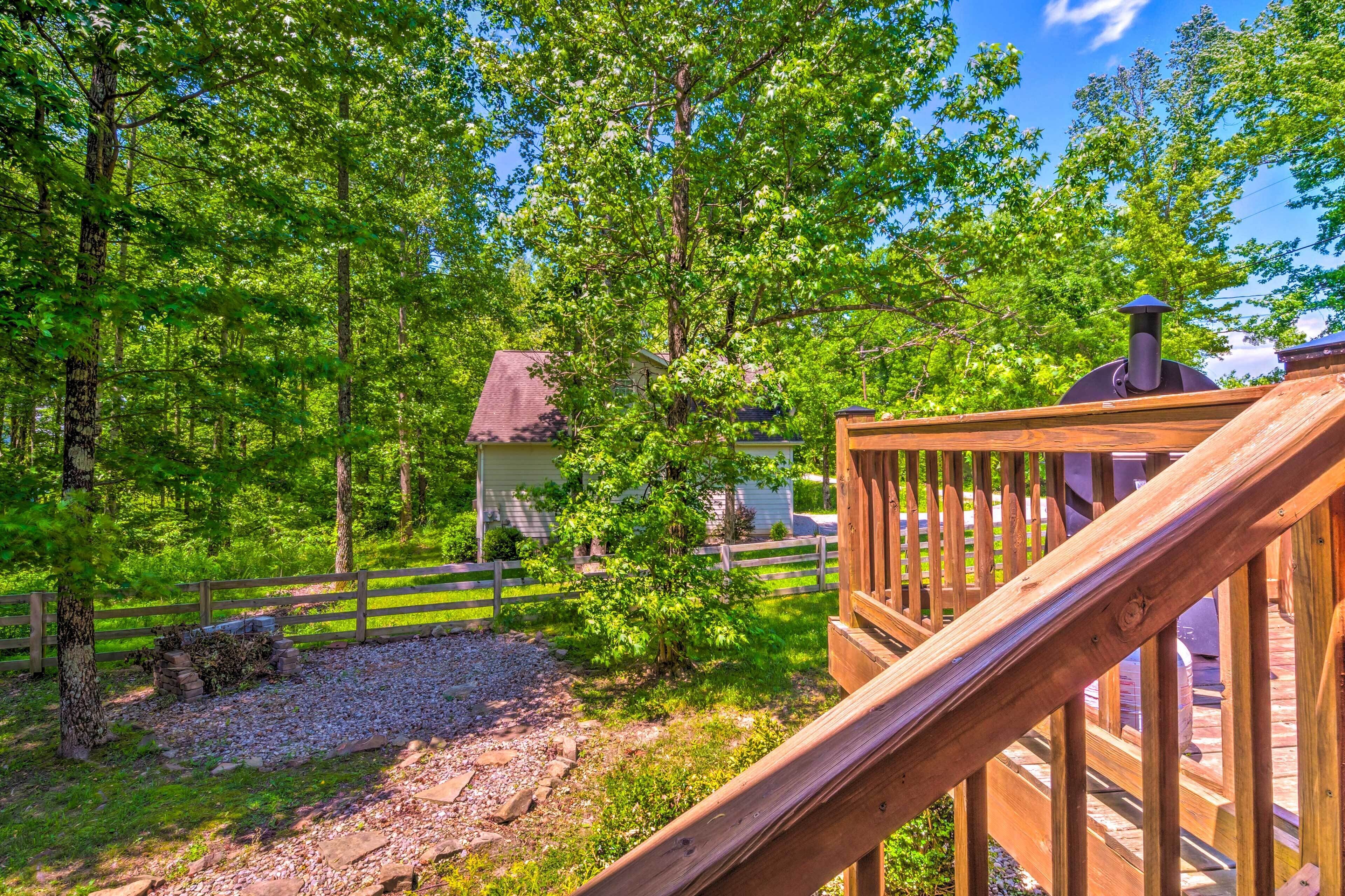 A wooden deck with a chimney, surrounded by lush greenery and trees.