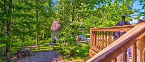 A wooden deck with a chimney, surrounded by lush greenery and trees.
