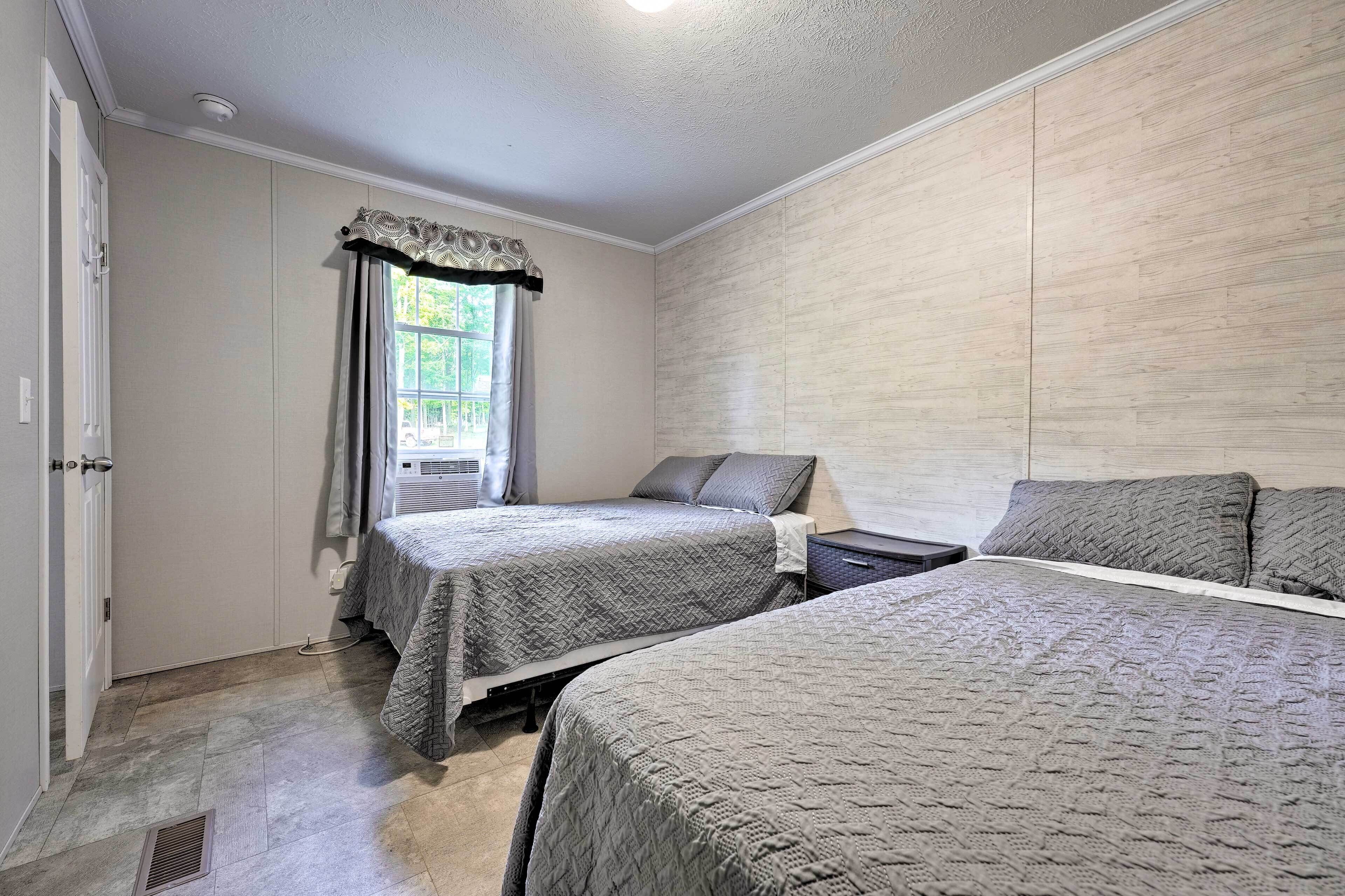 Un dormitorio con dos camas, una ventana con cortinas y una pared de madera.
